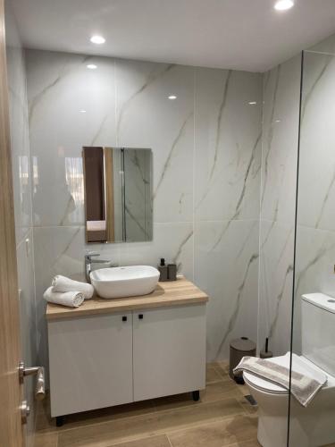 a white bathroom with a sink and a toilet at SunSea Studios close to the beach in Kato Gouves