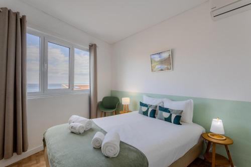 a bedroom with a large bed with towels on it at GuestReady - Beachside house with ocean view in Ponta Delgada