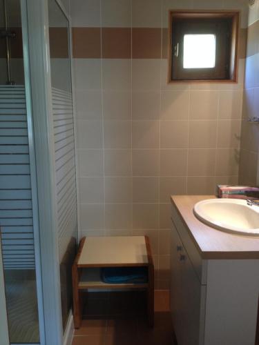 a bathroom with a sink and a shower and a stool at chalet dans les pins in Carcans