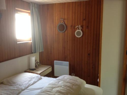a bedroom with a bed and a wooden wall at chalet dans les pins in Carcans