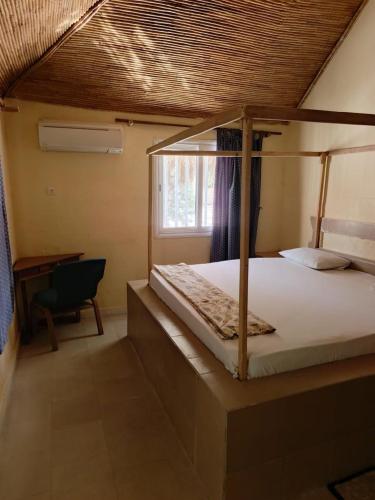 a bedroom with a canopy bed and a desk at A La Teranga in Poundiougne