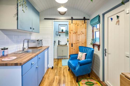 a kitchen with a blue chair and a sink at Host & Stay - Swallows Nest in Longridge