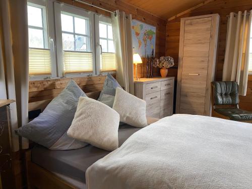 a bedroom with a bed with pillows and a chair at Charmantes Ferienhäuschen in Beetz - in 5 Minuten am See und im Wald in Kremmen