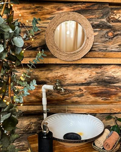 a bathroom sink with a mirror on a wooden wall at Cabaña el Leñador in Santa Elena