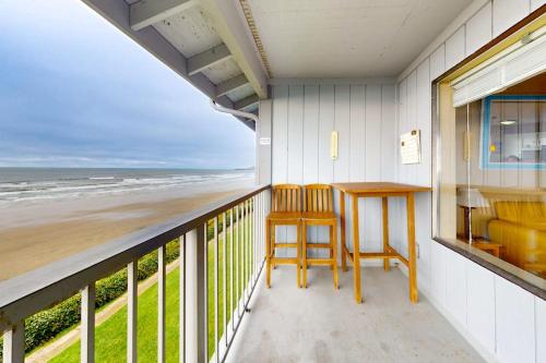 a balcony with a table and chairs and the beach at Oceanfront Nye Beach condo with gorgeous corner view & beach access in Newport