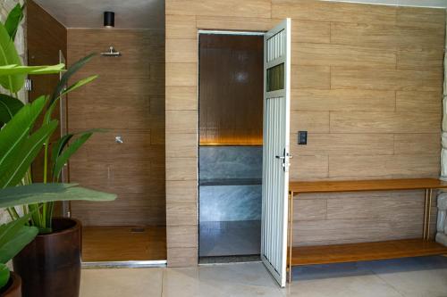 a bathroom with a wooden wall with a door at PALM BEACH Porto das Dunas, apartamento todo climatizado TÉRREO a 350 metros Beach Park in Aquiraz