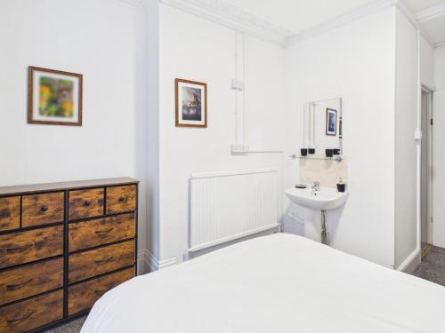 a white bedroom with a bed and a sink at Parkview Guest House in King's Lynn