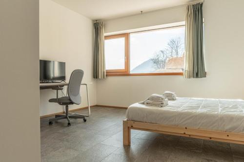 a bedroom with a bed and a desk and a window at Nest Family, Bedollo Ospitar in Bedollo