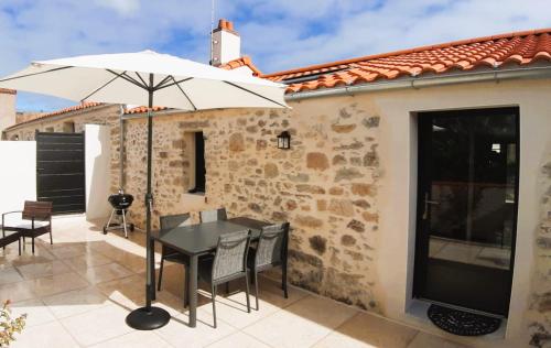 a patio with a black table and an umbrella at Gîtes Arvor et Tevenn in Saint-Brevin-les-Pins
