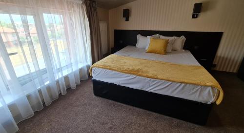 a bedroom with a large bed with a yellow blanket at Димоли in Elin Pelin