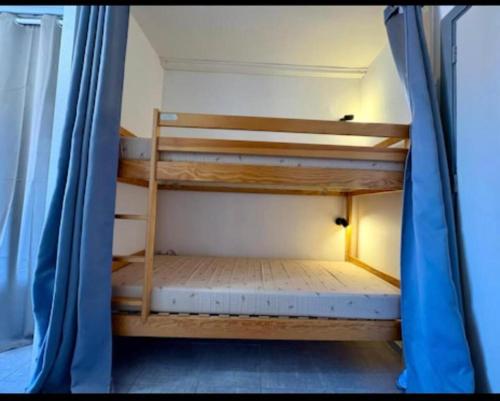 a room with two bunk beds with a blue curtain at Appartement Cap D'Agde in Cap d'Agde