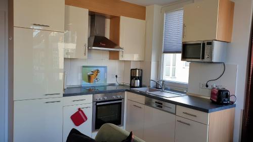 a kitchen with white cabinets and a stove top oven at Meerblick 9 - Großenbrode in Grossenbrode