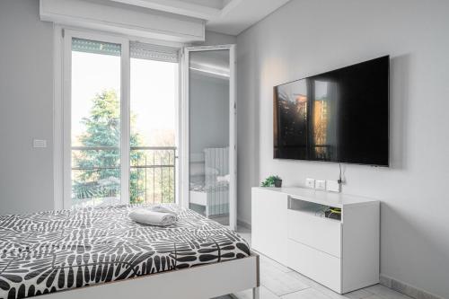 a white bedroom with a bed and a flat screen tv at Victory76 - Hospital, M3, Linate in San Donato Milanese