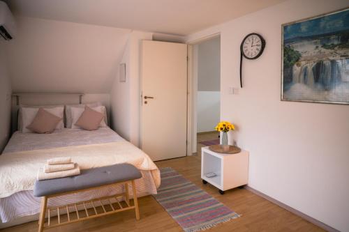 a bedroom with a bed and a clock on the wall at Kuća za odmor Kiljer - priroda, pogled i slavonski ugođaj in Grgurevići