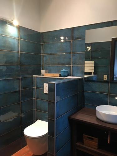 Ein blau gefliestes Badezimmer mit Toilette und Waschbecken in der Unterkunft Calicho in Urrugne