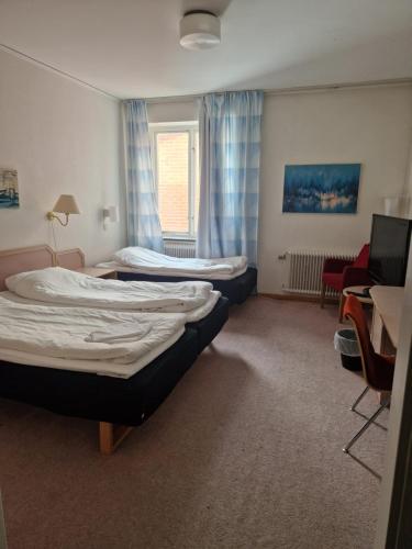 a room with two beds and a chair and a desk at Dorotea Logi B&B in Dorotea