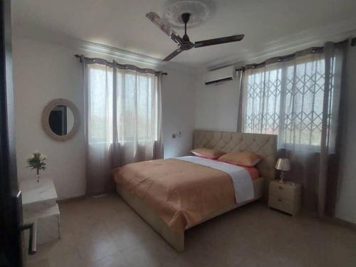 a bedroom with a bed and a ceiling fan at Monroe Luxury Apartments in Nsima