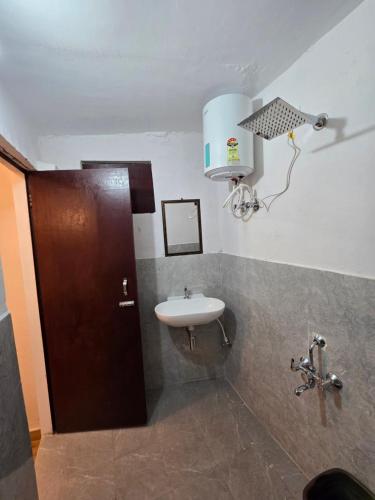 a bathroom with a sink and a brown door at Batohi hotel cafe & Restaurant in Devaprayāg