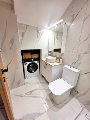 a white bathroom with a toilet and a washing machine at Anthouli Homes 1, steps from beach and centre in Kardamaina