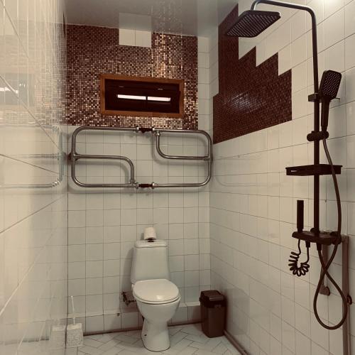 a white bathroom with a toilet and a shower at Brick House Melodies in Tsqaltubo