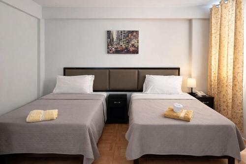 two beds in a hotel room with towels on them at Hotel Kuwasi in Chiclayo