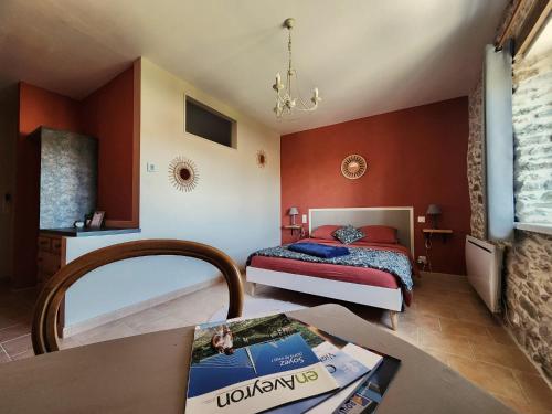 a bedroom with a bed and a table in a room at La Source Du Bonheur Chambres et Table d'Hôtes in Rieupeyroux