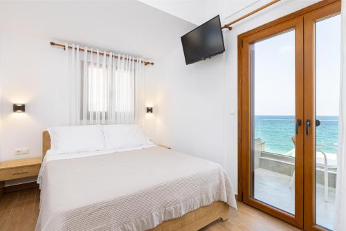 a bedroom with a bed and a balcony with the ocean at Azzure Studio in Kokkari