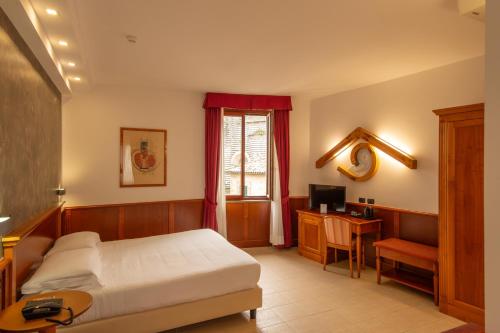 a bedroom with a bed and a desk and a television at Hotel Duomo - Etruria Collection in Orvieto