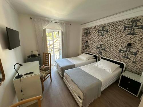 a hotel room with two beds and a tv at Hotel Cavaleiros De Cristo in Tomar
