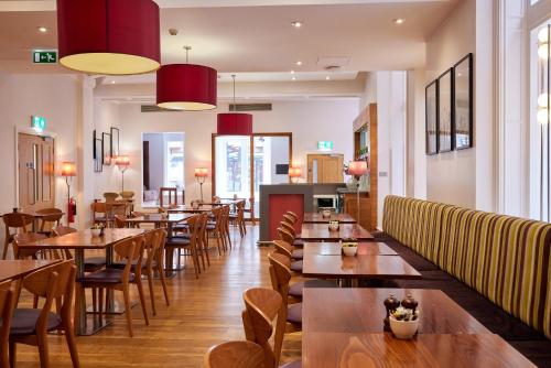 a restaurant with wooden tables and chairs at Thistle London Bloomsbury Park in London