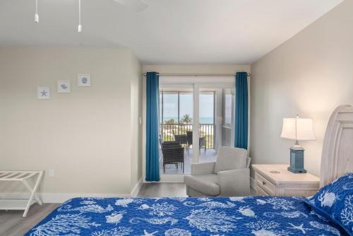 a bedroom with a bed and a chair and a window at Island Beach Club #P3E in Ybel
