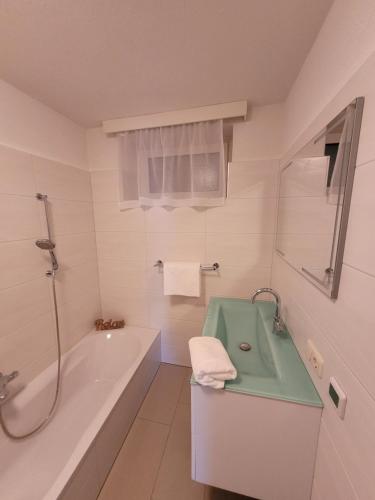 a white bathroom with a tub and a sink at Ferienwohnung Birkenhügel in Schörfling