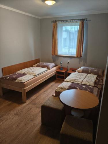 a room with two beds and a table in it at Zajazd U Doktora in Lubrza