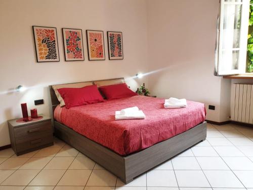 a bedroom with a bed with red sheets and red pillows at La Finestra sui Tigli in Mandello del Lario