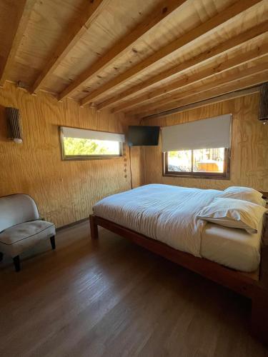 a bedroom with a large bed and a chair at CasaAndina in Malalcahuello