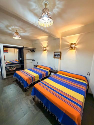 Zwei Betten in einem Zimmer mit Fernseher und Licht in der Unterkunft Hotel Yubazuu in San Pablo Villa de Mitla