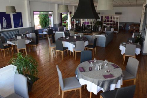 une salle à manger avec des tables et des chaises ainsi qu'un restaurant dans l'établissement Logis Le Petit Trianon, à Saint-Brévin-les-Pins