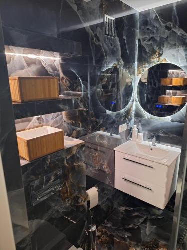a bathroom with a sink and a marble wall at Apartament Premium Tarnów 2 in Tarnów