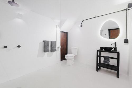 a white bathroom with a toilet and a mirror at Cocoon Oaxaca City- Curated Stay In Oaxaca Centro in Oaxaca City