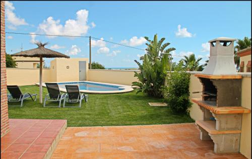 un patio trasero con piscina y sillas y una casa en Chalet Vigía 113, en Conil de la Frontera