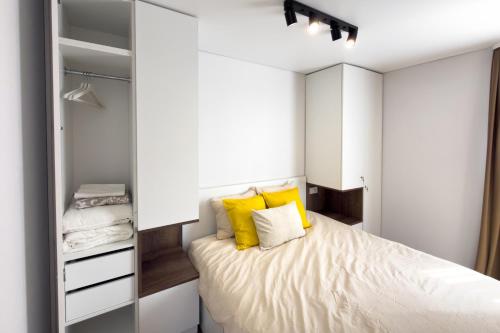 a small bedroom with a bed with yellow pillows at AC Vienibas Square apartments in Daugavpils