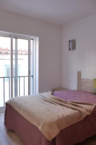 a bedroom with a bed with purple sheets and a balcony at Casas Luar da Aldeia - Apartamentos in Odeceixe