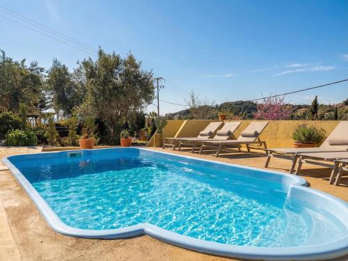 a swimming pool in the middle of a yard with lounge chairs at Villa Anafoufou Afionas with private heatable pool in Afionas