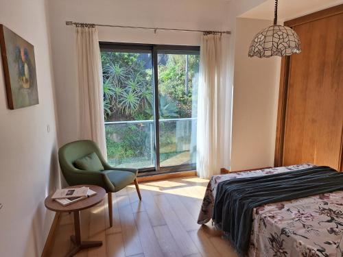 a bedroom with a bed and a chair and a window at Oceanus in Horta