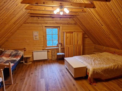 a bedroom in a log cabin with a bed and a desk at Sodyba Vovierių slėnis in Kuras