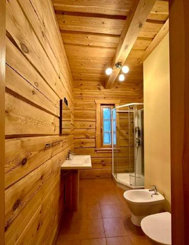 a wooden bathroom with two sinks and a shower at Sodyba Vovierių slėnis in Kuras