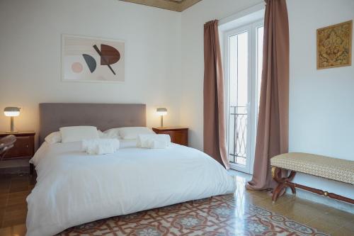 a bedroom with a large white bed and a window at Casa Martù in Palermo