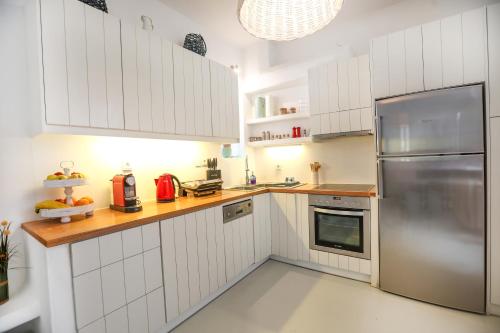 a kitchen with white cabinets and a stainless steel refrigerator at EMELIAS HOUSE SEA SIDE in Naxos Chora
