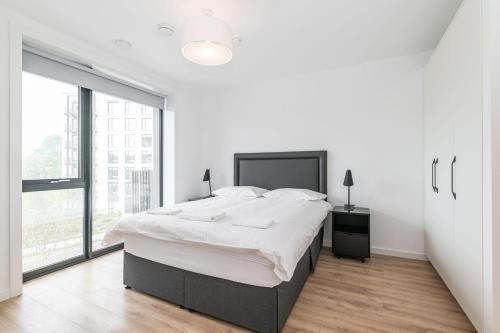 a white bedroom with a large bed and a large window at Grange One By Dublin At Home in Dublin
