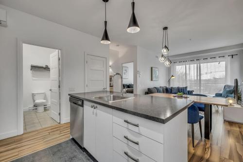 a kitchen with a sink and a living room at Initial Artsy Québec in Quebec City